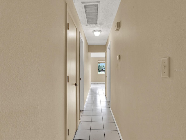 hall featuring light tile patterned floors and a textured ceiling