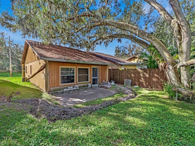 rear view of property featuring a patio area and a lawn