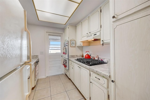 kitchen with white cabinetry, light tile patterned floors, and white appliances