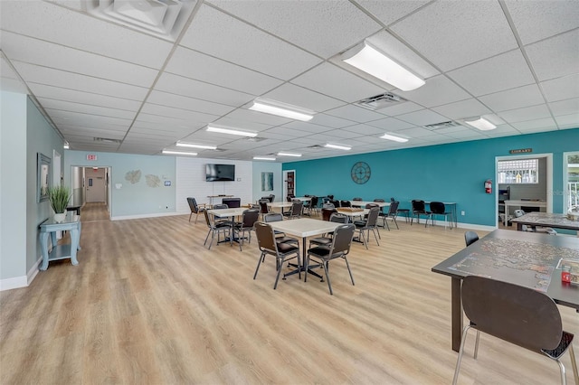 dining area featuring a drop ceiling and light wood-type flooring