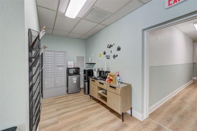 office featuring mail boxes, light hardwood / wood-style floors, and a drop ceiling