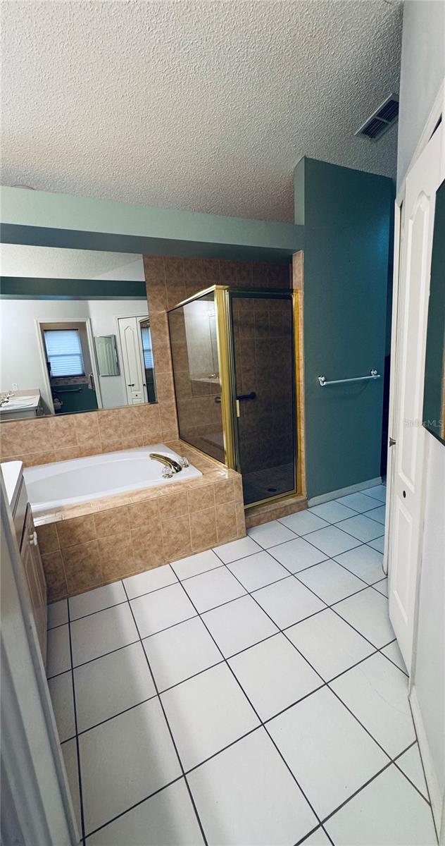 bathroom featuring vanity, tile patterned flooring, plus walk in shower, and a textured ceiling