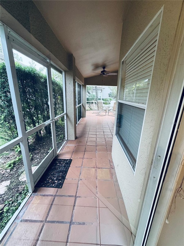 unfurnished sunroom with ceiling fan