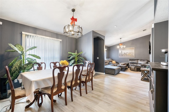 dining room featuring a chandelier, light hardwood / wood-style flooring, and vaulted ceiling