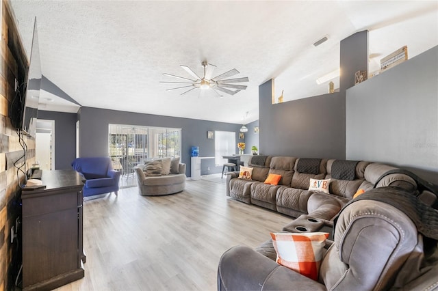 living room with light hardwood / wood-style floors, ceiling fan, a textured ceiling, and vaulted ceiling