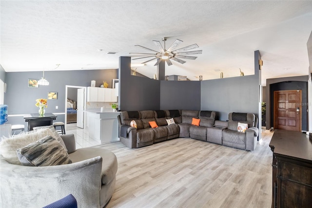 living room featuring light hardwood / wood-style flooring, lofted ceiling, a textured ceiling, and ceiling fan