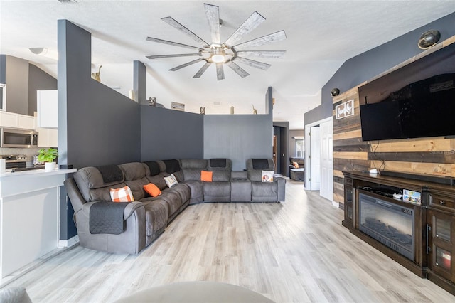 living room with ceiling fan, light hardwood / wood-style flooring, and vaulted ceiling