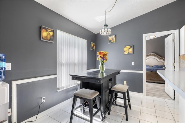 tiled dining area featuring a notable chandelier and lofted ceiling