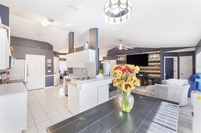 kitchen with stainless steel appliances, white cabinetry, sink, vaulted ceiling, and ceiling fan