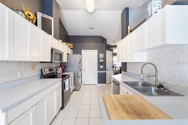 kitchen featuring light tile patterned flooring, wooden counters, white cabinetry, appliances with stainless steel finishes, and sink