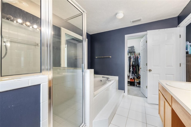 bathroom with vanity, independent shower and bath, tile patterned floors, and a textured ceiling