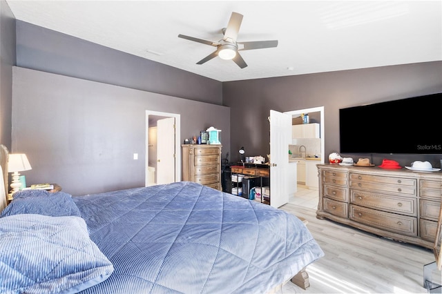 bedroom with ensuite bath, ceiling fan, and light hardwood / wood-style flooring