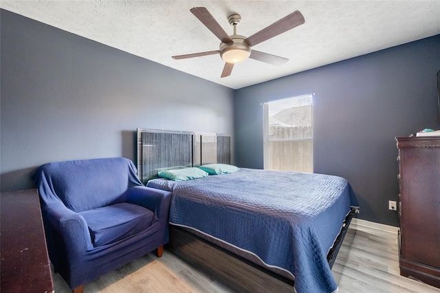 bedroom with a textured ceiling, light wood-type flooring, and ceiling fan