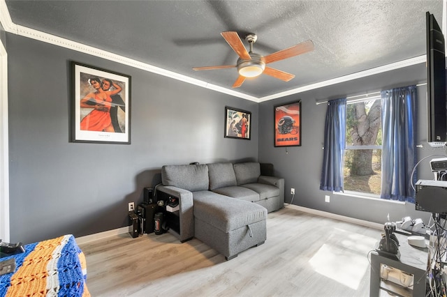 living room with ceiling fan, a textured ceiling, light hardwood / wood-style floors, and crown molding