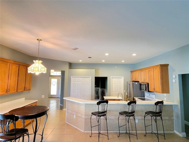 kitchen featuring pendant lighting, a kitchen breakfast bar, light tile patterned floors, appliances with stainless steel finishes, and kitchen peninsula