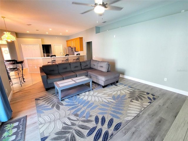 living room with ceiling fan with notable chandelier and light hardwood / wood-style flooring