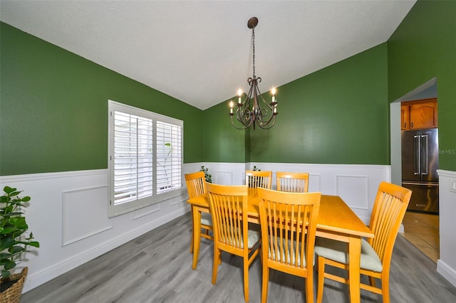 dining space with light hardwood / wood-style flooring, a chandelier, and lofted ceiling