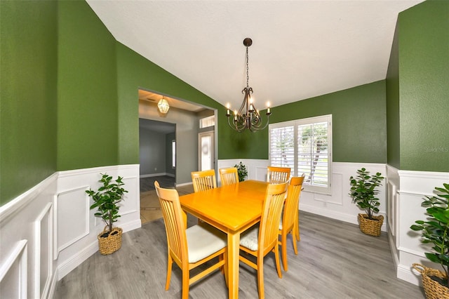 dining room with hardwood / wood-style flooring, lofted ceiling, and a chandelier