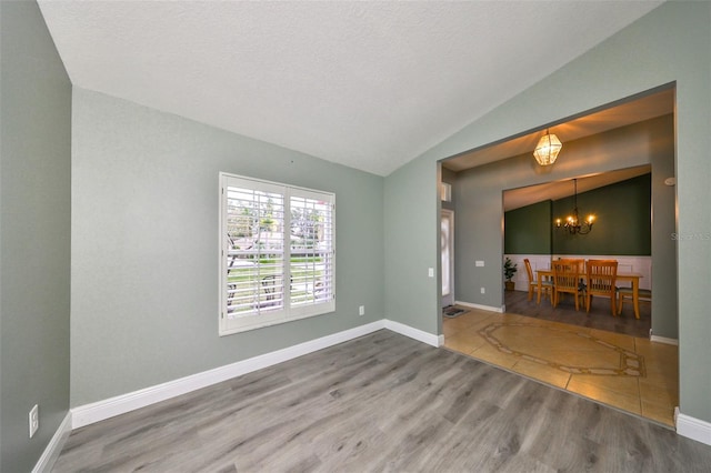 interior space featuring a textured ceiling, hardwood / wood-style floors, a chandelier, and vaulted ceiling