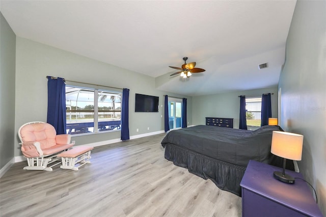 bedroom featuring ceiling fan, light hardwood / wood-style floors, and multiple windows