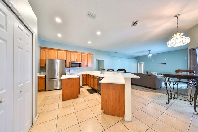 kitchen featuring hanging light fixtures, light tile patterned floors, an island with sink, kitchen peninsula, and stainless steel appliances