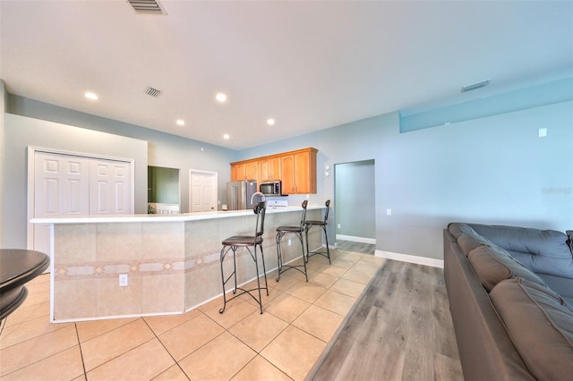 kitchen featuring light wood-type flooring, a breakfast bar area, and appliances with stainless steel finishes