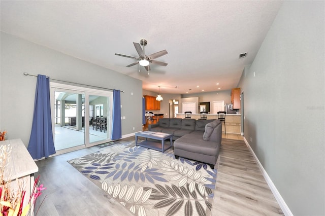 living room featuring ceiling fan, light hardwood / wood-style floors, a textured ceiling, and french doors