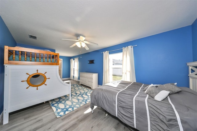 bedroom featuring hardwood / wood-style floors, ceiling fan, and a textured ceiling