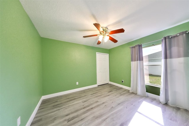 empty room with a textured ceiling, light hardwood / wood-style flooring, and ceiling fan