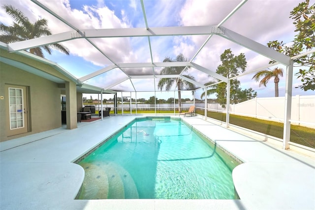 view of pool with glass enclosure and a patio