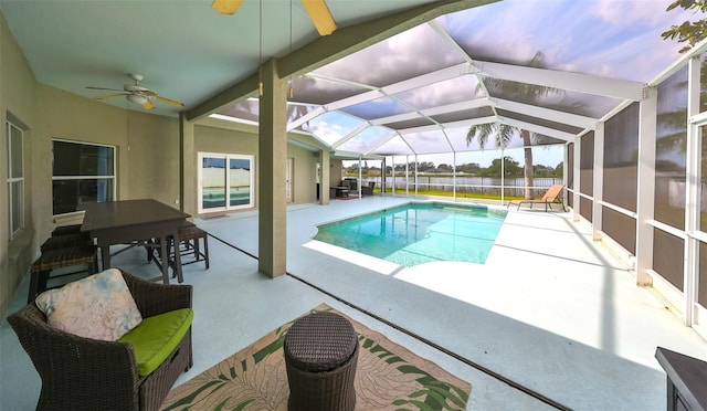 pool at dusk with glass enclosure, ceiling fan, and a patio