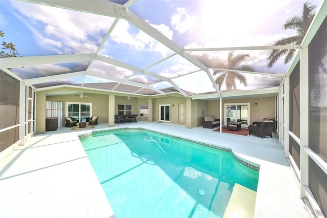 view of swimming pool featuring a patio, an outdoor living space, glass enclosure, and ceiling fan