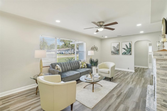 living room featuring ceiling fan, a fireplace, and light hardwood / wood-style floors