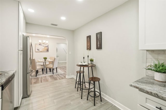 interior space with light stone countertops, appliances with stainless steel finishes, and white cabinetry