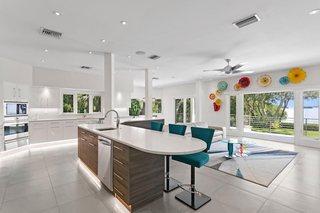 kitchen featuring light tile patterned floors, white cabinetry, a kitchen island with sink, and sink