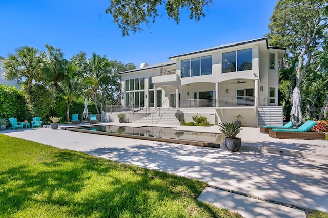 rear view of house featuring a yard, a balcony, ceiling fan, and a patio area