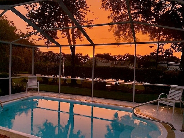 pool at dusk featuring glass enclosure