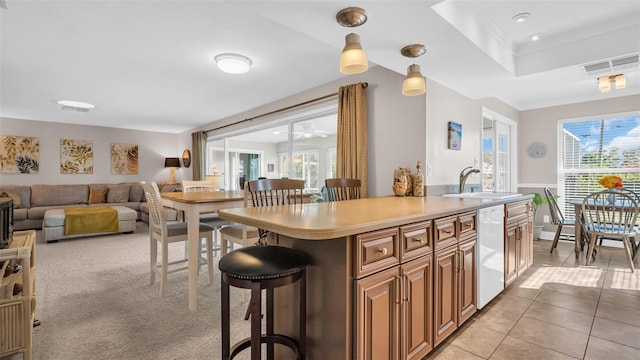 kitchen featuring pendant lighting, sink, a breakfast bar, white dishwasher, and a wealth of natural light