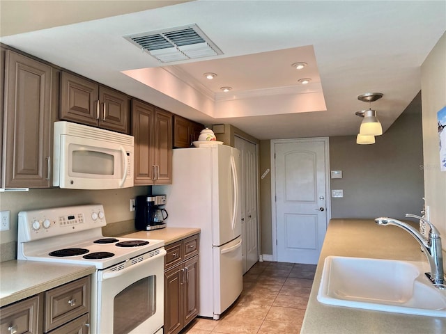 kitchen with white appliances, a tray ceiling, sink, and light tile patterned floors