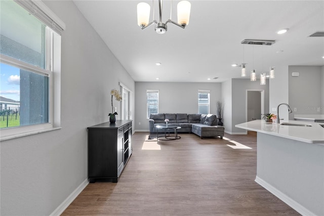 living room featuring wood-type flooring, sink, and an inviting chandelier