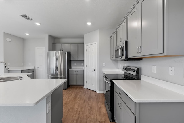 kitchen with stainless steel appliances, light hardwood / wood-style floors, sink, and gray cabinets