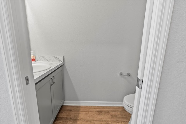 bathroom with hardwood / wood-style floors, vanity, and toilet