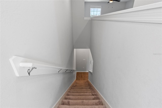 stairway featuring ceiling fan