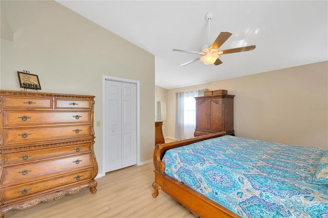 bedroom featuring ceiling fan, a closet, light hardwood / wood-style flooring, and vaulted ceiling