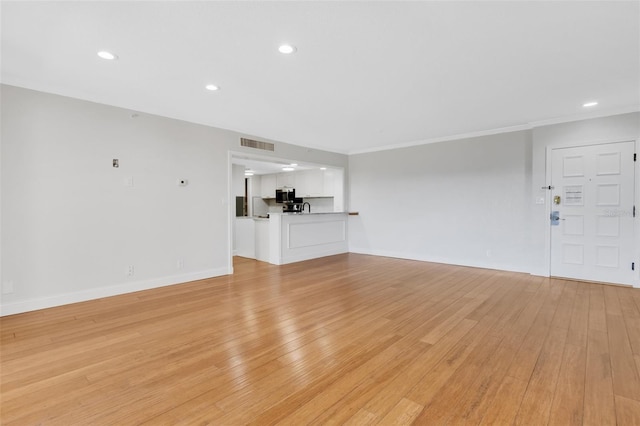 unfurnished living room with light wood-type flooring and crown molding