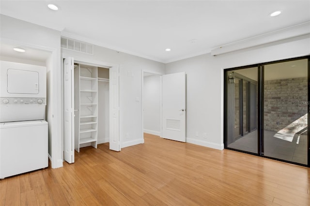 unfurnished bedroom featuring access to outside, light hardwood / wood-style floors, and stacked washer and clothes dryer