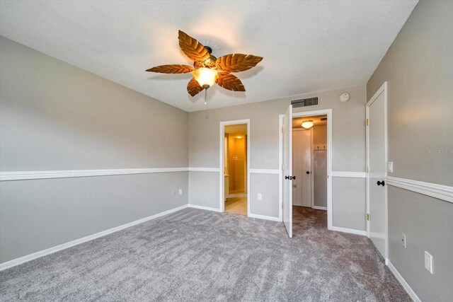 unfurnished bedroom with carpet flooring, ensuite bathroom, and ceiling fan