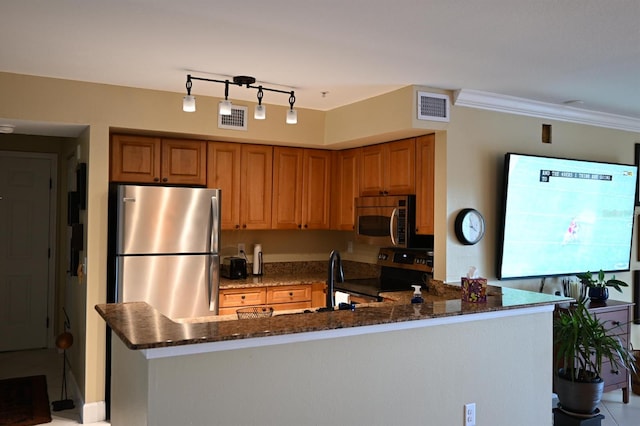 kitchen with kitchen peninsula, ornamental molding, appliances with stainless steel finishes, and dark stone counters