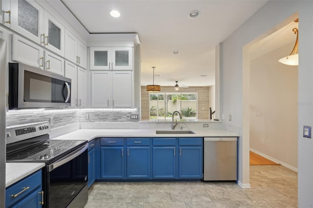 kitchen featuring appliances with stainless steel finishes, sink, blue cabinetry, decorative light fixtures, and white cabinetry