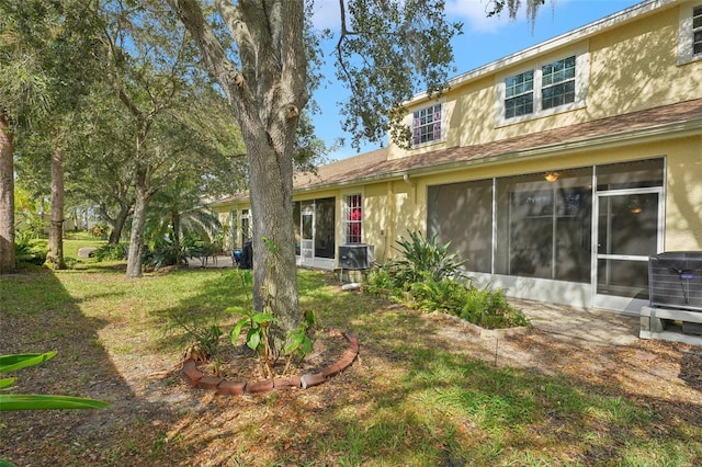 rear view of property featuring a sunroom, central air condition unit, and a lawn